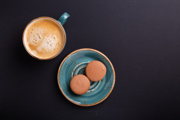 Blue cup of coffee and macaroons on the dark wooden table. Coffe break. Top view. Flat lay