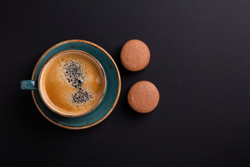 Blue cup of coffee and macaroons on the dark wooden table. Coffe break. Top view. Flat lay