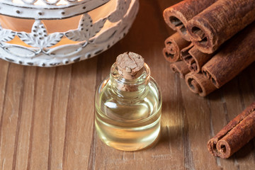 A bottle of cinnamon essential oil with cinnamon sticks