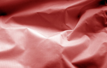 Crumpled transparent plastic surface in red color.