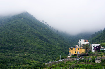 Liguria / Italy - June 25 / 2016: Houses of Corniglia by the foggy mountains of cinque terre