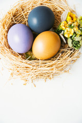 colored Easter eggs in nest on wooden background, selective focus image. Happy Easter card 