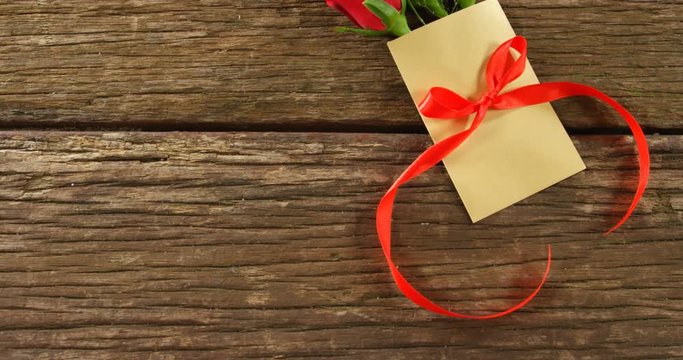 Bouquet of red roses on envelope with red ribbon on wooden surface 4k