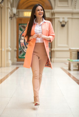 Young brunette woman in beige trousers and in a pink jacket