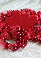 Background for greeting cards of love with beads and two hearts, with the effect of blur on a light background