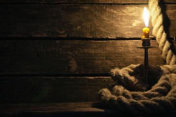 Obraz premium Lina do cumowania i płonąca świeca na stole kapitańskim piratów. Koncepcja podróży morskich.