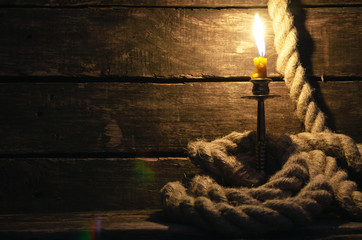 Mooring rope and burning candle on a pirate captain table. Sea travel concept.