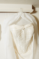 Fototapeta na wymiar A beautiful cream and clean Wedding dress Hanging in the hall of a hotel room. Wedding love fashion and celebration, wedding dress detail