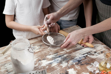 Obraz na płótnie Canvas Mom with children preparing the dough for pizza. Hands of mother and her children. Cooking with kids. Close-up