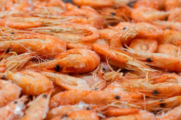 Fresh frozen waterless Atlantic twisted shrimps close-up. Macro photo of a counter with fresh-frozen orange shrimps.