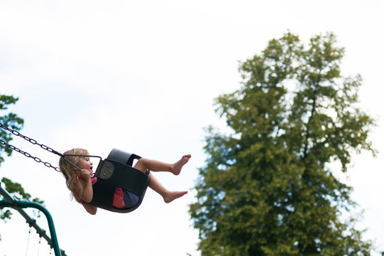 Side view of girl swinging on swing in park