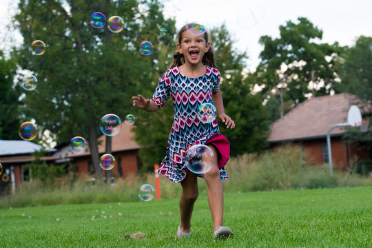 Cheerful girl playing with bubbles outdoors