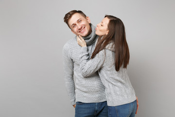 Naklejka premium Young cute couple girl guy in gray sweaters, scarves together isolated on grey wall background, studio portrait. Healthy lifestyle, ill sick disease treatment, cold season concept. Mock up copy space.