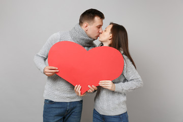 Obraz na płótnie Canvas Young cute couple girl guy in gray sweaters, scarves kissing isolated on grey wall background, studio portrait. Healthy lifestyle, ill sick disease treatment, cold season concept. Mock up copy space.