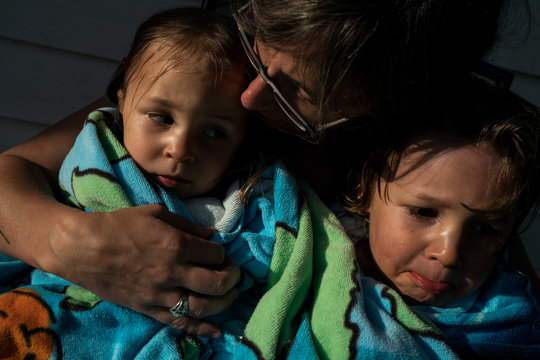 Mother holding daughters wrapped in towel