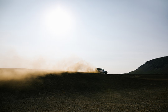 Car moving on dirt road against sky