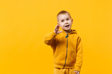 Little cute kid boy 3-4 years old wearing yellow clothes isolated on bright orange wall background,...