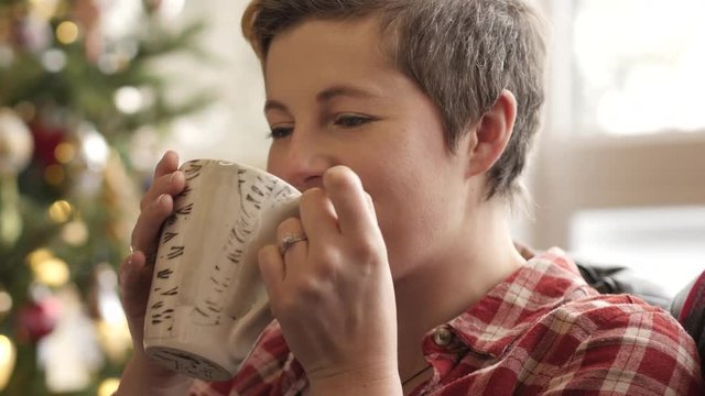 Blonde woman sips her tea and smiles.