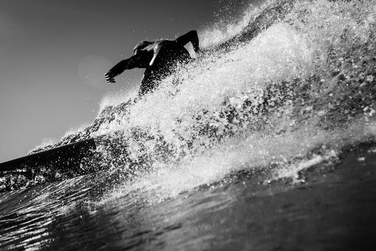 Rear view of surfer surfing in sea against sky