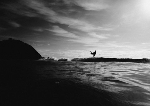 Surfer surfing in sea against cloudy sky
