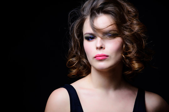 Woman with curly hairstyle and makeup on black background. Makeup idea for elegant outfit. Professional makeup. Attractive elegant lady with smoky eyes makeup and pink lipstick. Beauty salon concept