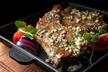 Fried chicken legs with garlic, onions and herbs, in a black frying pan