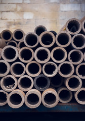 An industrial stack of empty paper cardboard tube rolls waiting to be recycled in a warehouse...