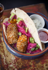Beautiful lebanese falafel and salad in a pitta bread, served with spicy sauce, mayo and shots of alcohol spirits. Served in a ceramic bowl on a metal canister.