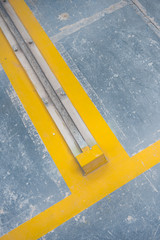 A yellow floor warning parking line on a textured floor inside a car park or industrial factory floor. dusty smooth and vibrant hazard warning.
