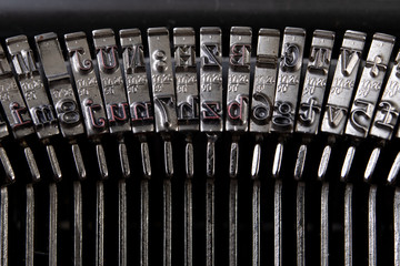 Font in a typewriter. Metal stamps for imprinting letters on a white sheet.