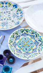 hand painted plates lie on the table, painted plates, plates on a white table, plates with paintings (vertically)