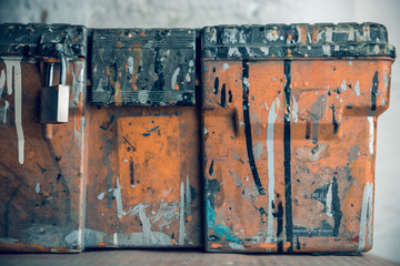 Artistic colourful ink and paint drips on a orange textured toolbox background in an industrial...