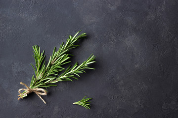 Rosemary herbs on dark stone background. Top view. Copy space.