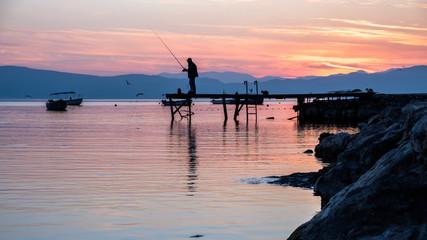 Silhouette of a a fisherman on a jetty at Lake Ohrid, Macedonia, during sunset