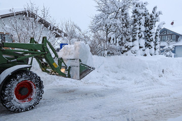 Schneeräumen einer Straße mit einem Traktor. Im Winter wird in einem Dorf die Straße mit einem...