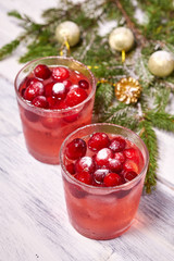 Glasses with cranberry juice on white wooden background with pine branch in the background. Christmas tree