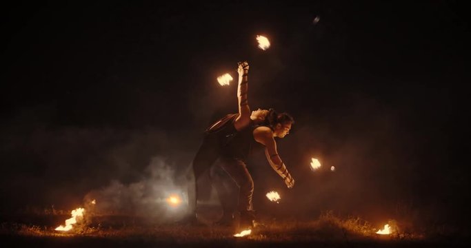 Coll fire show artists having a performance in the dark, swinging fire pieces between bowls with burning liquid - extreme slow motion