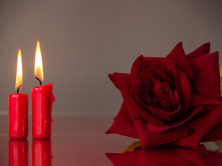 Fototapeta na wymiar Concept of love Red candles lit and a red rose with a warm background