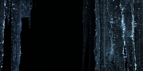 Winter night background. Glittering icicles isolated on black background, blue tones, panoramic view - obrazy, fototapety, plakaty