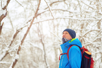Happy man, traveler walking in the winter forest during snowfall