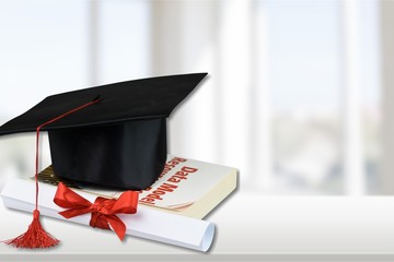 Graduation mortarboard on top of stack of books on  background