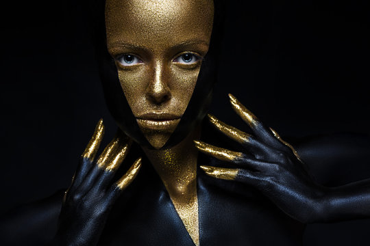 High fashion model with black and gold leather, golden fingers. Isolated on black background Beauty female face, creative make-up.
