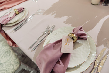 Festive table serving. Wedding banquet. Festive table decorated with white plate with pastel pink napkin, cutlery, glasses. Top view, close up