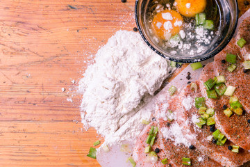 Raw Pork Loin chops on a cutting board with herbs, rosemary, thyme, chilli, salt, pepper on white...