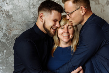Mother and her adult sons. Happiness. Two adult sons kiss and hugs their beloved mother. Mother's happiness