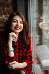 Obraz premium Female portrait. Amazing smiling girl in a red dress with a beautiful charismatic smile and red lipstick on her lips