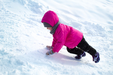 Fototapeta na wymiar little girl is climbing an ice hill