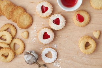 Fototapeta na wymiar Top view of traditional Linzer cookies filled with strawberry jam on wooden board with heart-shaped openings