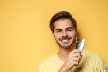 Portrait of young man with toothbrush and paste on color background. Space for text