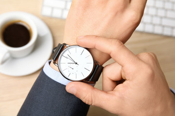 Businessman with wrist watch working at office table, closeup. Time management